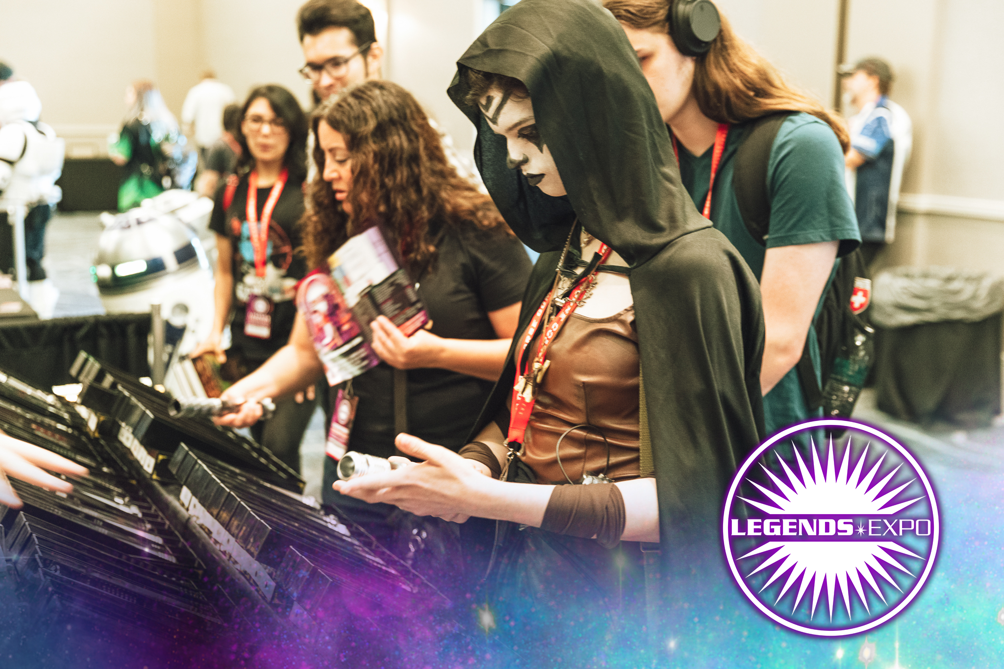 A con goer in cosplay at Legends Expo shopping for lightsabers at a vendor booth.