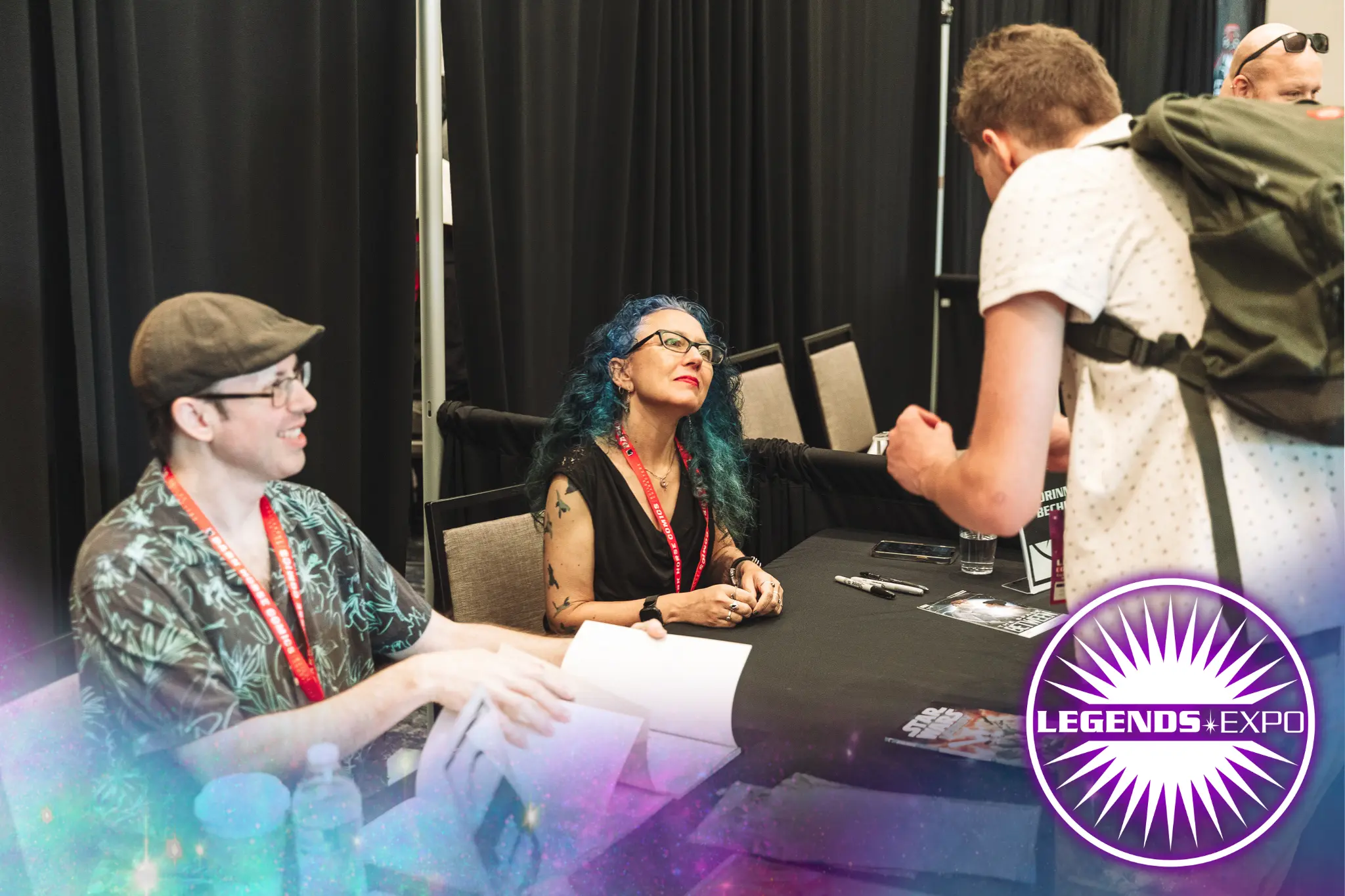 Con goers meeting writers and getting their books signed.