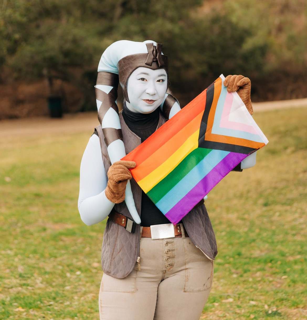 Lorie Lorie in her Mission Vao cosplay holding a pride flag.
